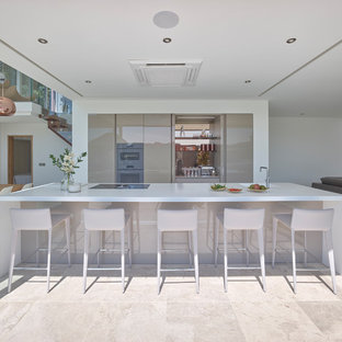 Photo of a large contemporary single-wall open plan kitchen in Other with flat-panel cabinets, beige cabinets, composite countertops, mirror splashback, limestone flooring, an island, beige floors and white worktops.