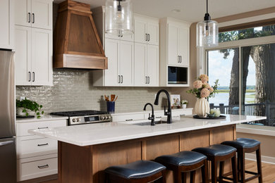 Example of a mid-sized transitional galley vinyl floor and brown floor open concept kitchen design in Minneapolis with an undermount sink, shaker cabinets, white cabinets, quartz countertops, green backsplash, subway tile backsplash, stainless steel appliances, an island and white countertops