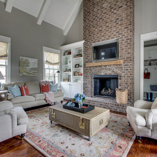 Inspiration for a mid-sized traditional open concept family room in Nashville with grey walls, medium hardwood floors, a standard fireplace, a brick fireplace surround and a wall-mounted tv.