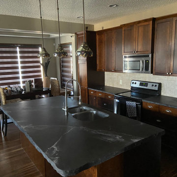 Kitchen with charcoal tops and natural white veins complimented with texture.