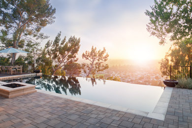 Hot tub - large contemporary backyard brick and custom-shaped infinity hot tub idea in Orange County