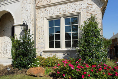 Inspiration for a mid-sized traditional front yard full sun garden for spring in Dallas with natural stone pavers.