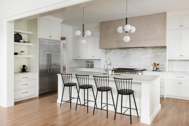 Open concept kitchen - large transitional galley light wood floor and brown floor open concept kitchen idea in Nashville with a single-bowl sink, beaded inset cabinets, white cabinets, marble countertops, white backsplash, stone slab backsplash, stainless steel appliances, an island and white countertops