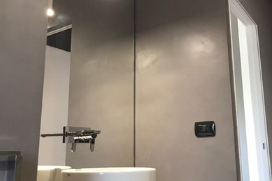 This is an example of a small contemporary powder room in Turin with medium wood cabinets, a one-piece toilet, multi-coloured tile, porcelain tile, grey walls, a vessel sink, laminate benchtops and grey floor.