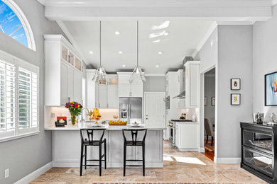 Mid-sized transitional u-shaped limestone floor, beige floor and vaulted ceiling open concept kitchen photo in San Francisco with an undermount sink, recessed-panel cabinets, white cabinets, quartz countertops, white backsplash, marble backsplash, stainless steel appliances, a peninsula and white countertops
