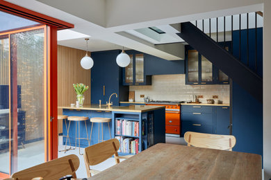 Design ideas for a medium sized modern galley kitchen in London with a built-in sink, shaker cabinets, blue cabinets, copper worktops, white splashback, porcelain splashback, integrated appliances and an island.