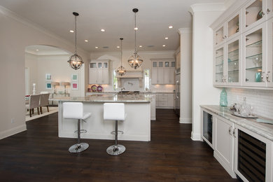 Large transitional galley dark wood floor eat-in kitchen photo in Tampa with a farmhouse sink, shaker cabinets, white cabinets, granite countertops, white backsplash, subway tile backsplash, stainless steel appliances and two islands
