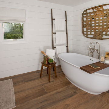 Soaking tub with shiplap wall and wood look tile floor
