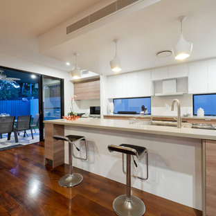 This is an example of a contemporary galley eat-in kitchen in Brisbane with an undermount sink, flat-panel cabinets, light wood cabinets, window splashback, dark hardwood floors, with island, brown floor and beige benchtop.