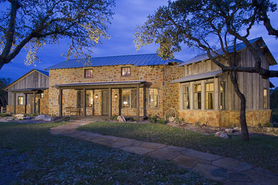 Mid-sized country two-storey brown exterior in Austin with stone veneer.