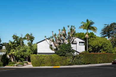 Example of a mid-sized trendy gray two-story stucco exterior home design in Los Angeles with a shingle roof and a gray roof