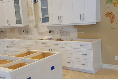 Inspiration for a large modern l-shaped travertine floor and beige floor eat-in kitchen remodel in Miami with an undermount sink, shaker cabinets, white cabinets, quartzite countertops, white backsplash, glass tile backsplash, stainless steel appliances, an island and white countertops