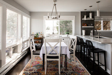 Inspiration for a mid-sized transitional kitchen/dining combo in Seattle with white walls, dark hardwood floors, a standard fireplace, a tile fireplace surround and brown floor.