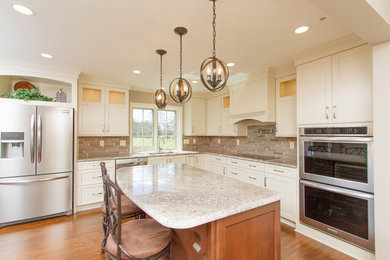Inspiration for a large timeless l-shaped medium tone wood floor eat-in kitchen remodel in Other with a double-bowl sink, recessed-panel cabinets, white cabinets, granite countertops, multicolored backsplash, ceramic backsplash, stainless steel appliances and an island