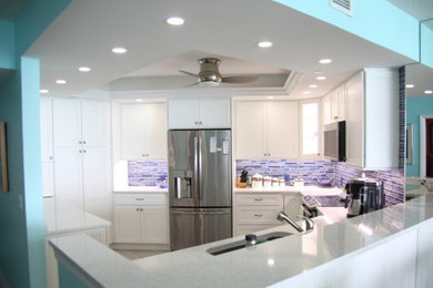 Inspiration for a coastal gray floor and tray ceiling kitchen remodel in Miami with a drop-in sink, shaker cabinets, glass tile backsplash and stainless steel appliances