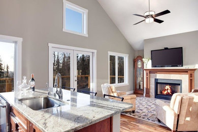 Inspiration for a large timeless medium tone wood floor family room remodel in Other with a bar, gray walls, a standard fireplace, a wall-mounted tv and a wood fireplace surround