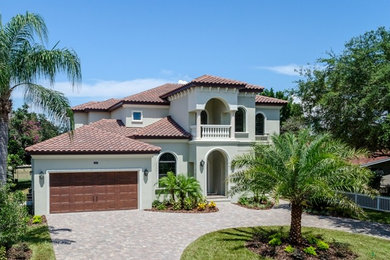 Design ideas for a large mediterranean two-storey stucco exterior in Tampa.