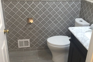 Bathroom - small contemporary 3/4 gray tile and porcelain tile porcelain tile and gray floor bathroom idea in Las Vegas with furniture-like cabinets, black cabinets, a two-piece toilet, gray walls, an undermount sink and marble countertops