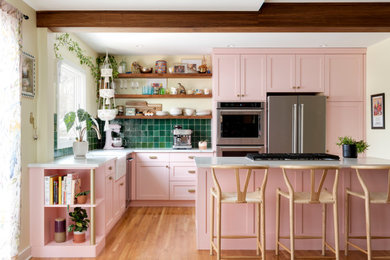 ミネアポリスにある高級な中くらいなエクレクティックスタイルのおしゃれなキッチン (エプロンフロントシンク、ピンクのキャビネット、クオーツストーンカウンター、緑のキッチンパネル、シルバーの調理設備、淡色無垢フローリング、ベージュの床、白いキッチンカウンター、シェーカースタイル扉のキャビネット、テラコッタタイルのキッチンパネル) の写真