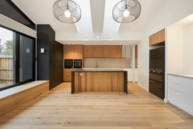 Inspiration for a mid-sized modern light wood floor eat-in kitchen remodel in Melbourne with a drop-in sink, marble countertops, multicolored backsplash, subway tile backsplash, black appliances, an island and black countertops