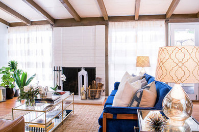 Example of a mid-sized trendy formal and open concept medium tone wood floor living room design in Los Angeles with gray walls, a standard fireplace, a brick fireplace and no tv