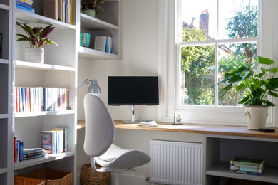 Modelo de despacho minimalista pequeño con paredes blancas, moqueta, escritorio empotrado y suelo gris