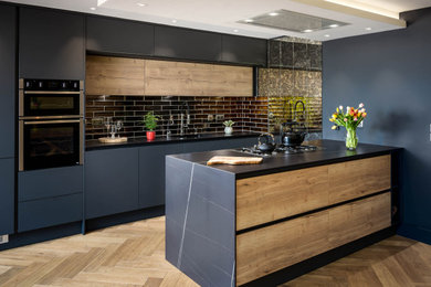 Design ideas for a medium sized contemporary galley kitchen in Dublin with flat-panel cabinets, black cabinets, composite countertops, glass tiled splashback and a breakfast bar.