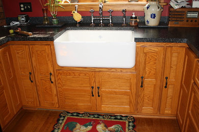 Mid-sized cottage dark wood floor eat-in kitchen photo in Milwaukee with a triple-bowl sink, recessed-panel cabinets, medium tone wood cabinets, tile countertops, red backsplash and no island