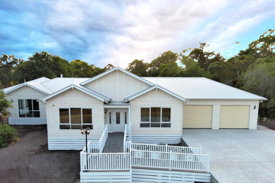 Country one-storey white house exterior in Melbourne with wood siding, a gable roof, a metal roof, a white roof and clapboard siding.