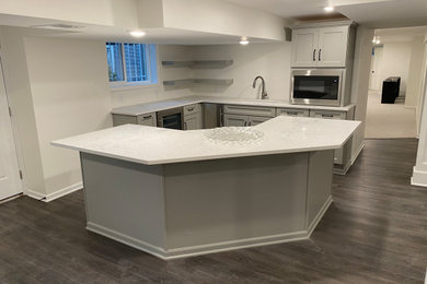 Mid-sized transitional l-shaped dark wood floor open concept kitchen photo in Kansas City with an undermount sink, shaker cabinets, gray cabinets, quartzite countertops, stainless steel appliances, an island and white countertops