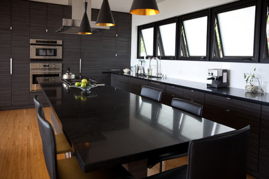 Open concept kitchen - mid-sized modern u-shaped medium tone wood floor open concept kitchen idea in Hawaii with a single-bowl sink, flat-panel cabinets, dark wood cabinets, granite countertops, stainless steel appliances and an island
