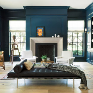 Photo of a transitional home office in Houston with a library, blue walls, light hardwood floors, a standard fireplace and a freestanding desk.