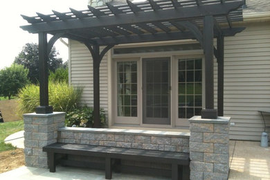 Mid-sized arts and crafts backyard stone patio photo in Philadelphia with a pergola