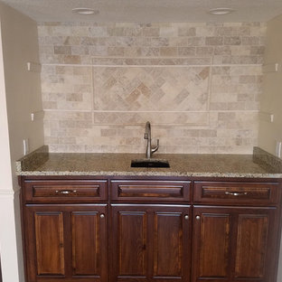 リトルロックの中サイズのトラディショナルスタイルのおしゃれなウェットバー (淡色無垢フローリング、アンダーカウンターシンク、レイズドパネル扉のキャビネット、茶色いキャビネット、御影石カウンター、ベージュキッチンパネル、スレートの床、茶色い床、ベージュのキッチンカウンター) の写真