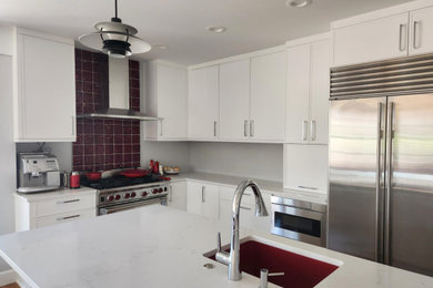 Example of a mid-sized trendy l-shaped open concept kitchen design in Seattle with an undermount sink, shaker cabinets, white cabinets, quartz countertops, red backsplash, stainless steel appliances, an island and white countertops