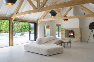 Réalisation d'un salon design avec un sol en carrelage de porcelaine, un poêle à bois, un manteau de cheminée en pierre, un sol beige et un plafond voûté.