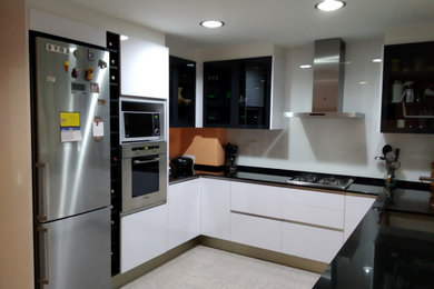 Foto de cocinas en U minimalista con armarios con paneles lisos, encimera de granito, salpicadero de vidrio, suelo de baldosas de cerámica y encimeras negras