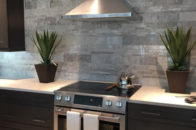 Example of a mid-sized trendy porcelain tile and beige floor open concept kitchen design in Miami with a single-bowl sink, shaker cabinets, brown cabinets, quartzite countertops, gray backsplash, marble backsplash, stainless steel appliances and an island