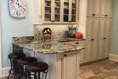 Inspiration for a large transitional galley porcelain tile enclosed kitchen remodel in Other with an undermount sink, raised-panel cabinets, distressed cabinets, granite countertops, beige backsplash, stone tile backsplash, stainless steel appliances and a peninsula