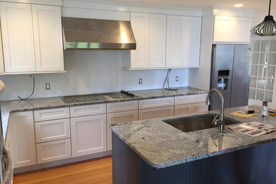 This is an example of a transitional l-shaped eat-in kitchen in Bridgeport with an undermount sink, shaker cabinets, white cabinets, soapstone benchtops, stainless steel appliances, light hardwood floors and with island.