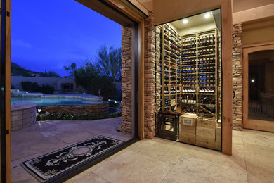 This is an example of a small mediterranean wine cellar in Phoenix with travertine floors, storage racks and beige floor.