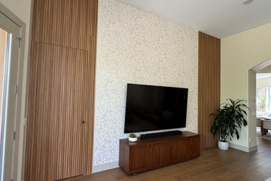 Example of a medium tone wood floor and wall paneling family room design in Phoenix with no fireplace and a wall-mounted tv