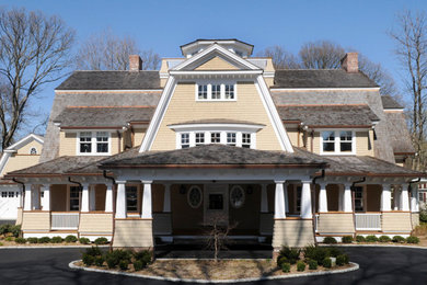 Mid-sized traditional two-storey yellow house exterior in New York with wood siding, a gable roof and a shingle roof.