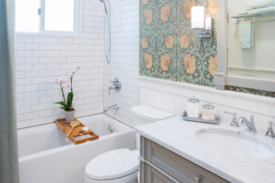 Small traditional bathroom in Sacramento with shaker cabinets, grey cabinets, an alcove tub, a shower/bathtub combo, a two-piece toilet, white tile, ceramic tile, ceramic floors, an undermount sink, marble benchtops, white floor, a shower curtain, white benchtops, a single vanity, a freestanding vanity and wallpaper.