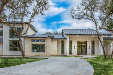 Example of a large cottage white two-story stucco exterior home design in Austin with a metal roof