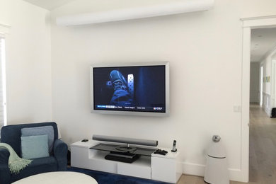 Mid-sized minimalist open concept medium tone wood floor home theater photo in Los Angeles with white walls and a projector screen