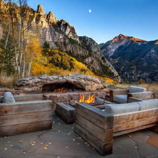 デンバーの巨大なラスティックスタイルのおしゃれな裏庭のテラス (天然石敷き、日よけなし、ファイヤーピット) の写真