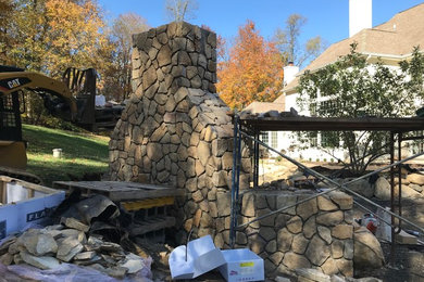 Example of a large mountain style backyard stone patio design in Philadelphia with a fire pit and no cover