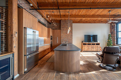 Example of a small urban galley medium tone wood floor, brown floor and exposed beam kitchen design in Other with an undermount sink, flat-panel cabinets, medium tone wood cabinets, stainless steel appliances and a peninsula