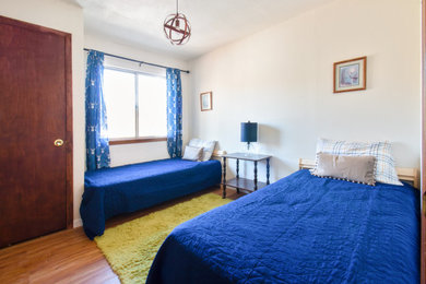 Diseño de habitación de invitados retro grande con paredes blancas, suelo de madera en tonos medios y suelo marrón